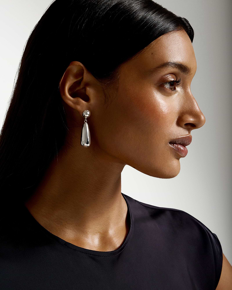Profile of a model wearing sterling silver Jasmine drop earrings and a black top.