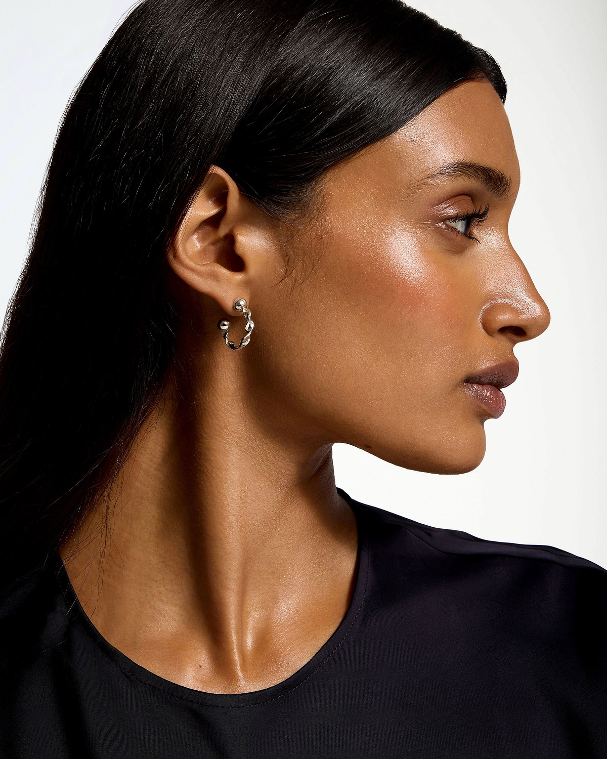 Woman in profile wearing sterling silver crescent twisted hoop earring.