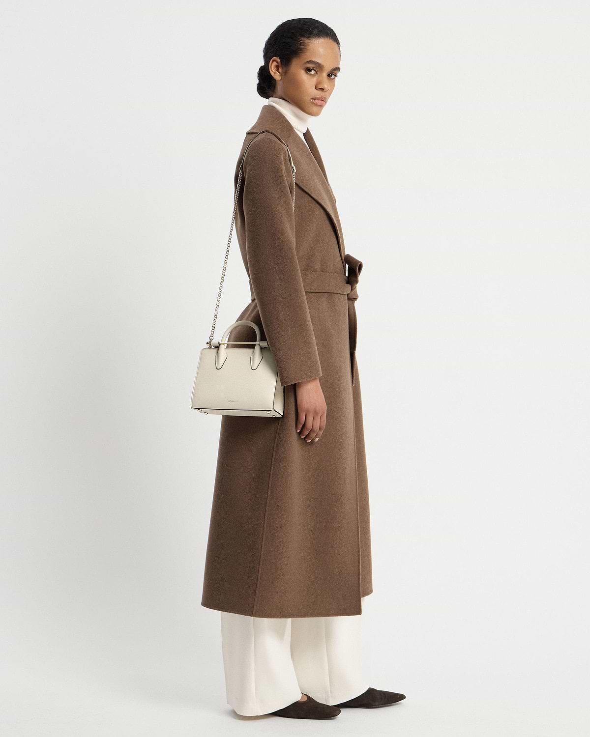 Model wearing a brown coat carrying a vanilla mini tote with chain shoulder strap.