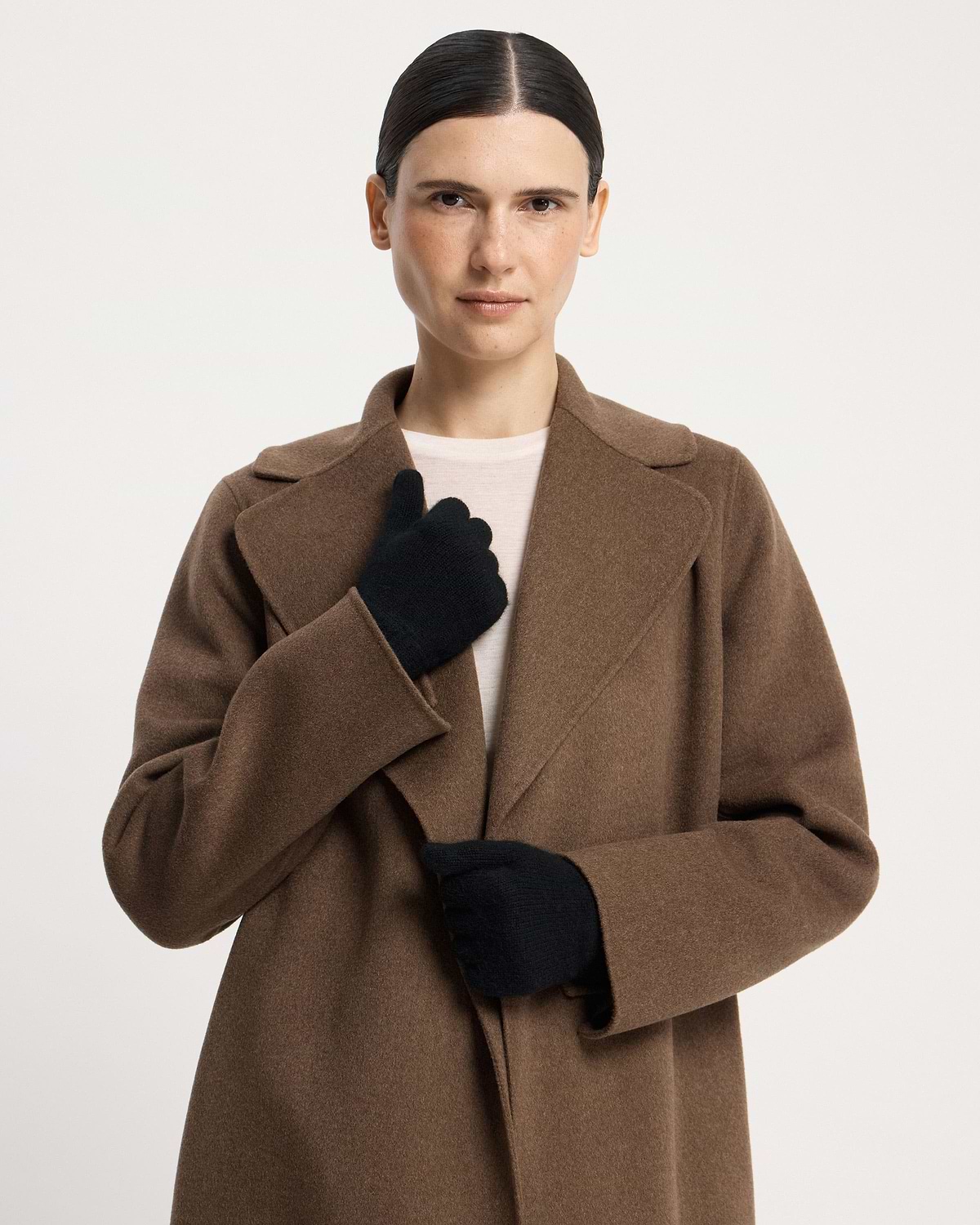 Model wearing black cashmere gloves and brown coat, facing camera.