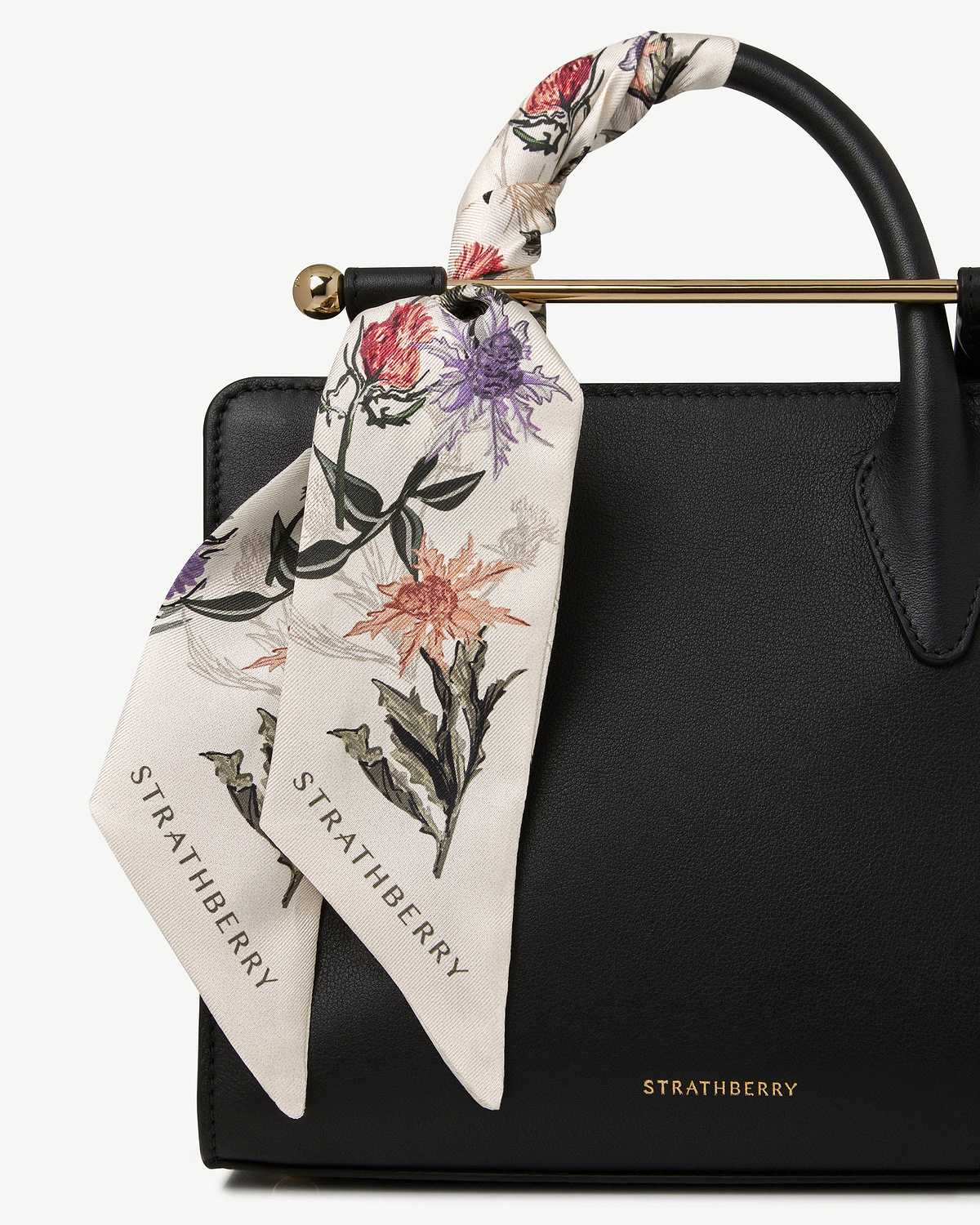 Silk skinny scarf in vanilla with forest green thistle print tied to Strathberry bag.