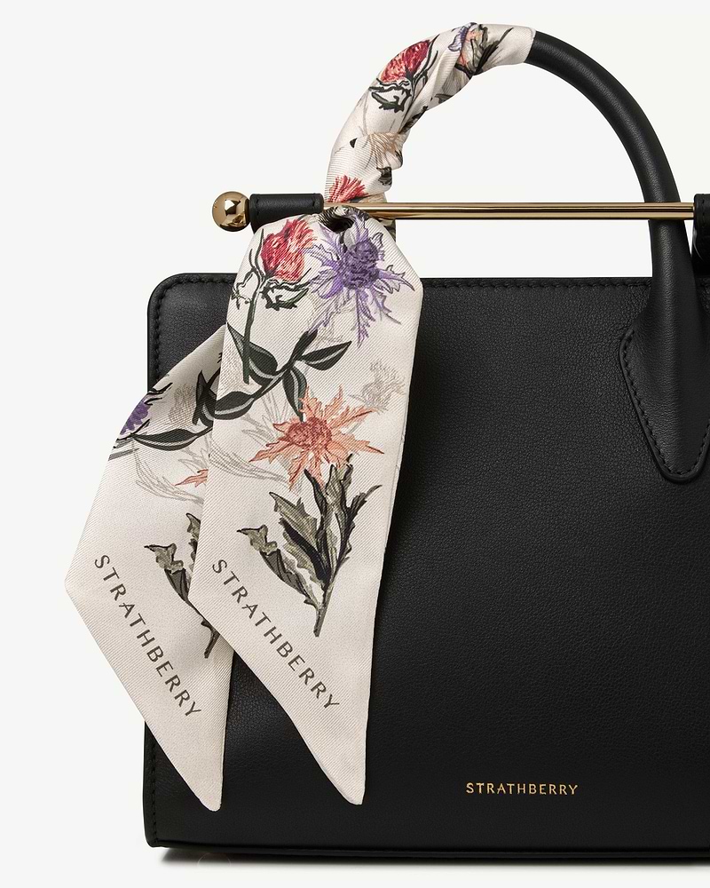 Silk skinny scarf in vanilla with forest green thistle print tied to Strathberry bag.