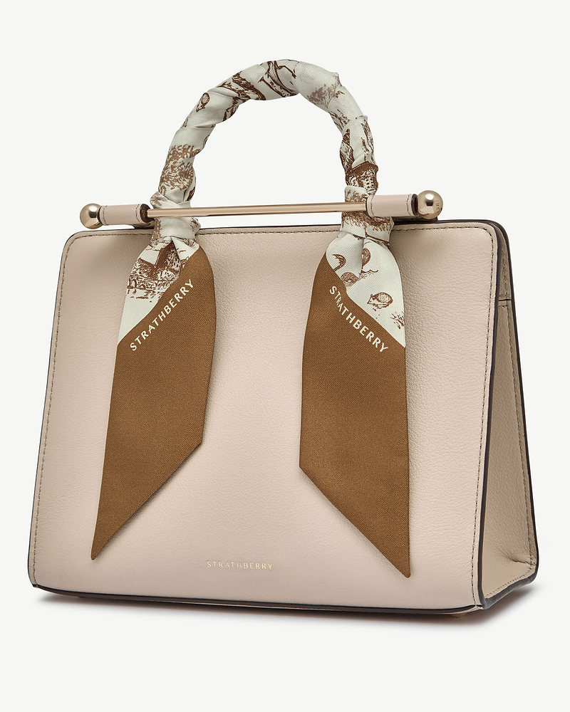 Silk skinny scarf in tan and vanilla animal print tied around beige handbag handle, Strathberry.