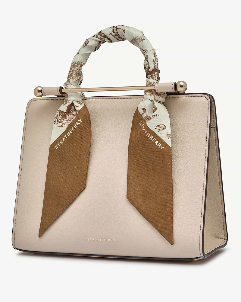 Silk skinny scarf in tan and vanilla animal print tied around beige handbag handle, Strathberry.