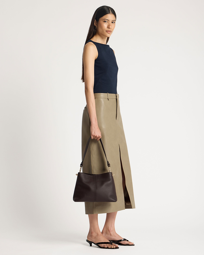 Model holding espresso leather hobo bag at her side, strap and hardware visible.