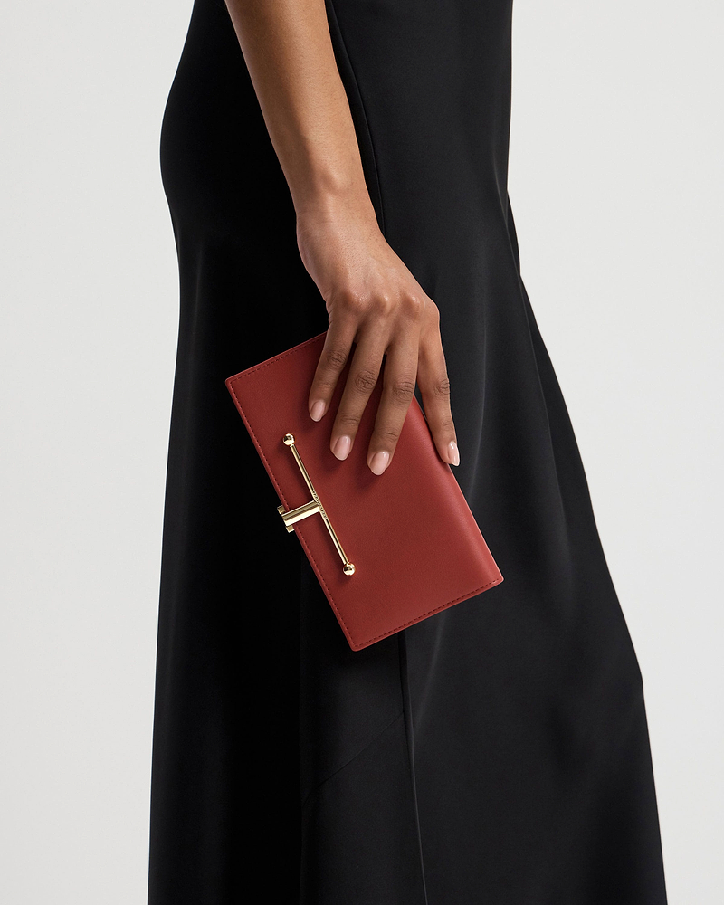 Hand holding Levanto red large Melville Street wallet with gold bar hardware.