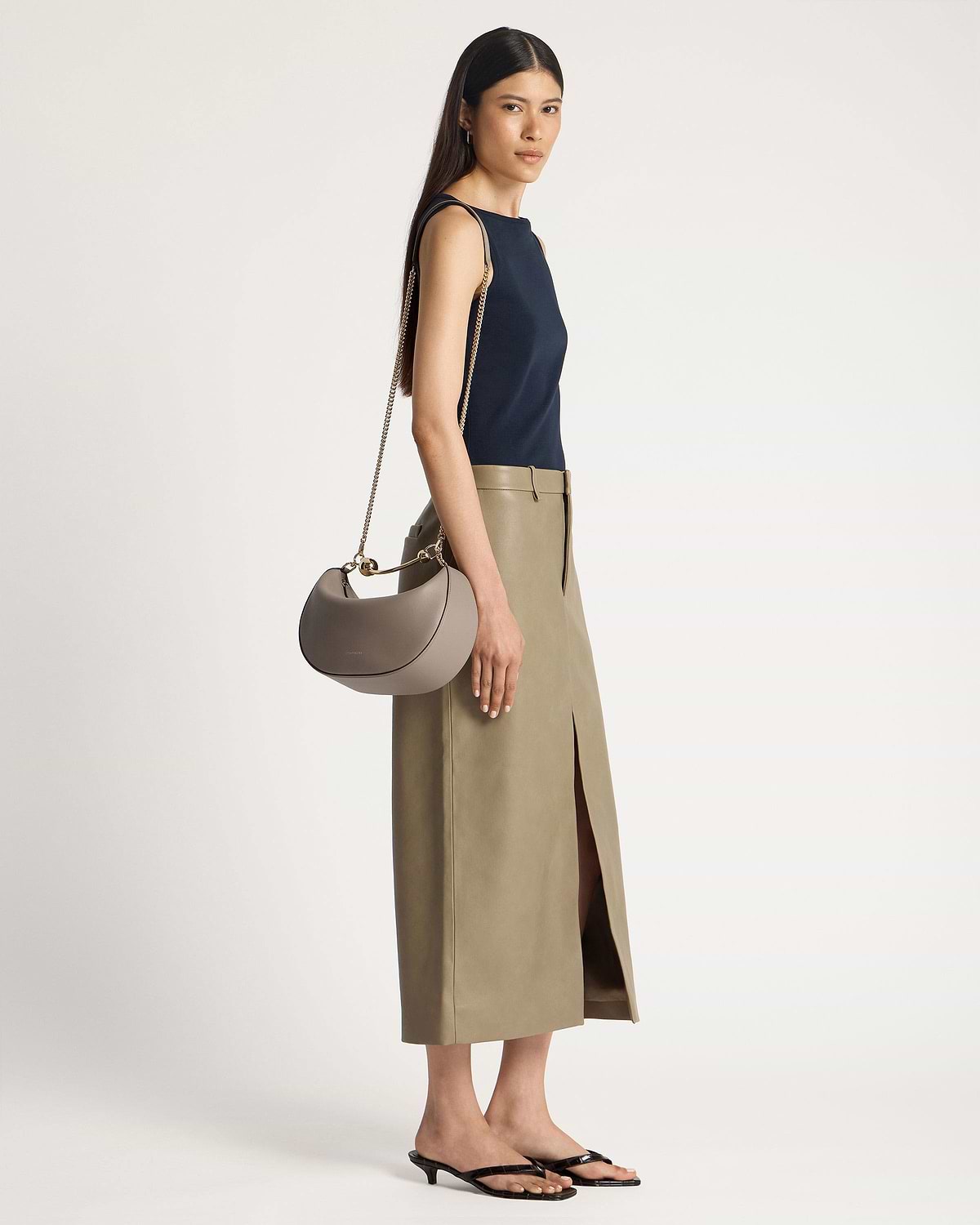 Model wearing a taupe crescent moon shoulder bag with gold chain strap