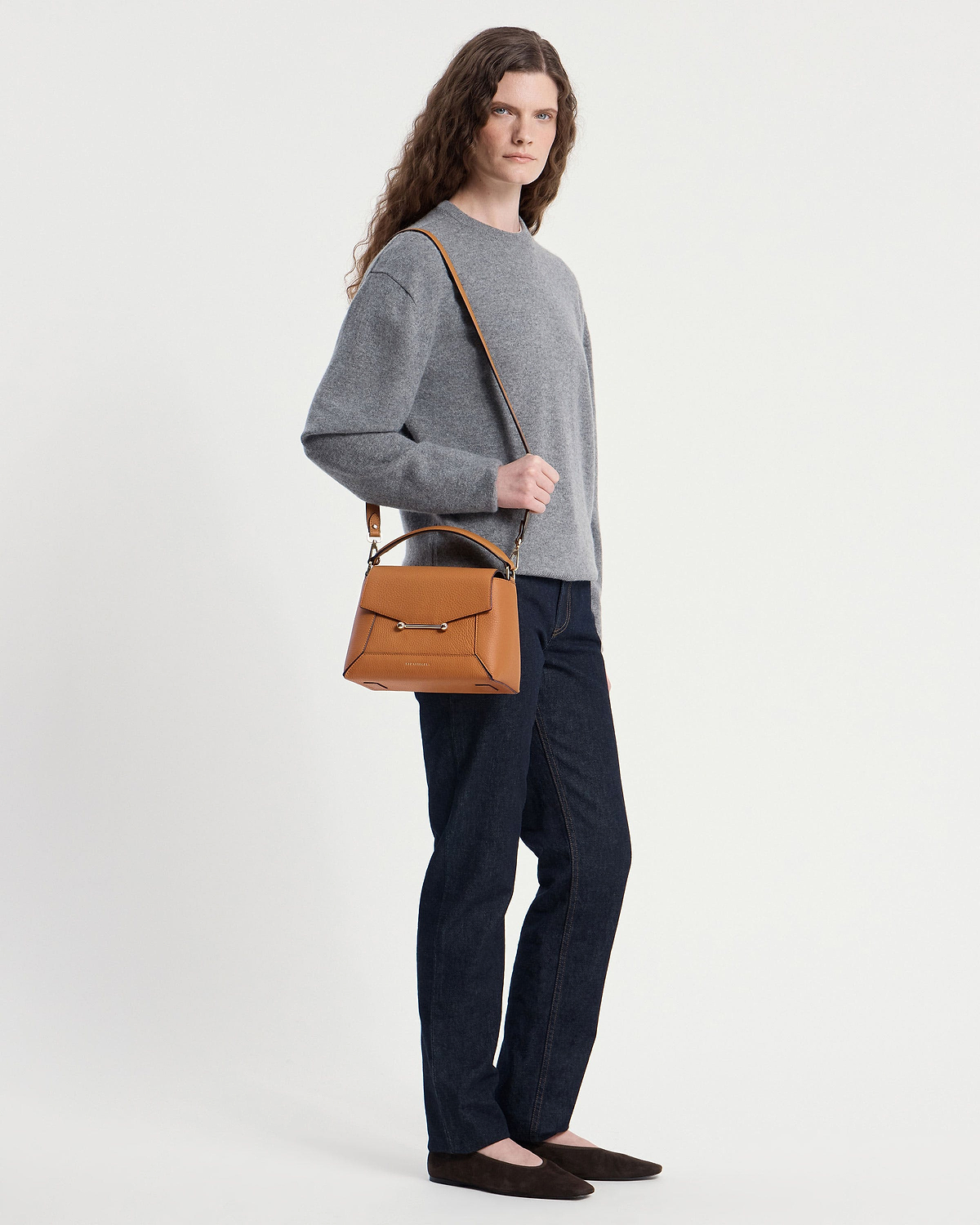 Model wearing a grey jumper and jeans carrying a honey mosaic bag over her shoulder.
