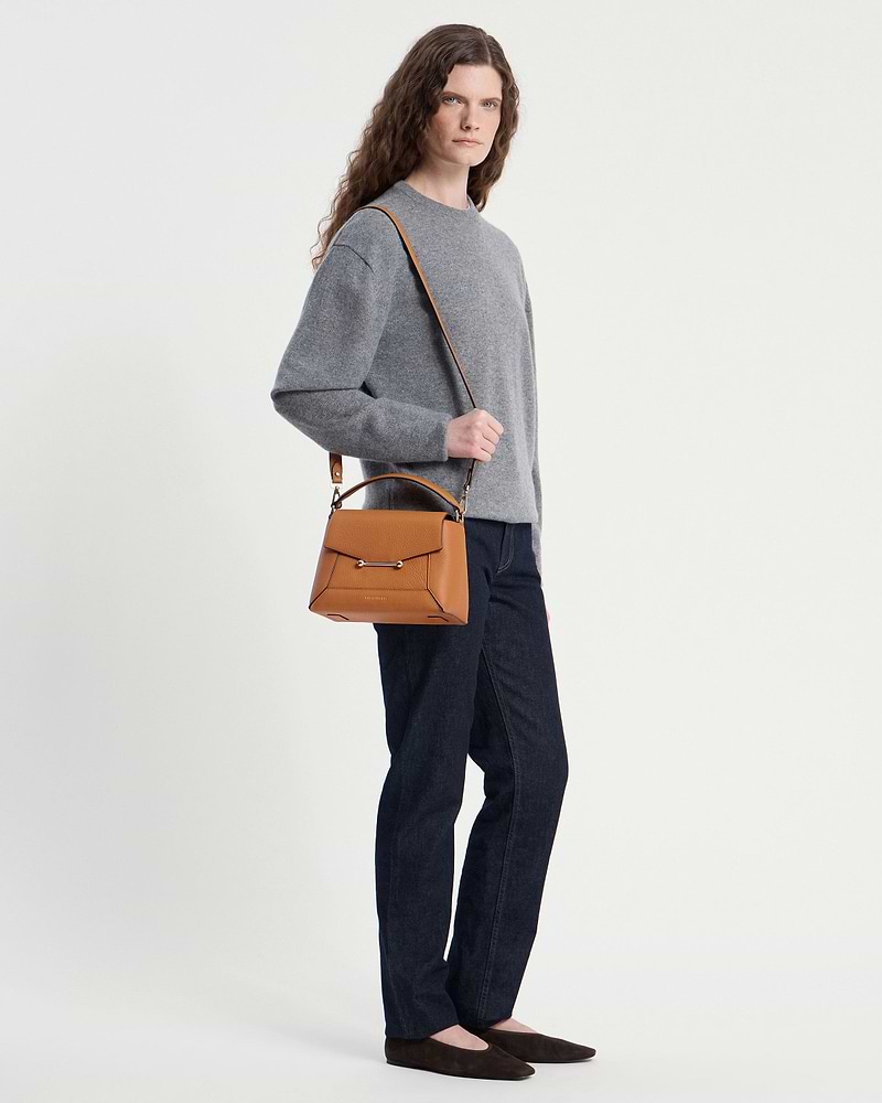 Model wearing a grey jumper and jeans carrying a honey mosaic bag over her shoulder.