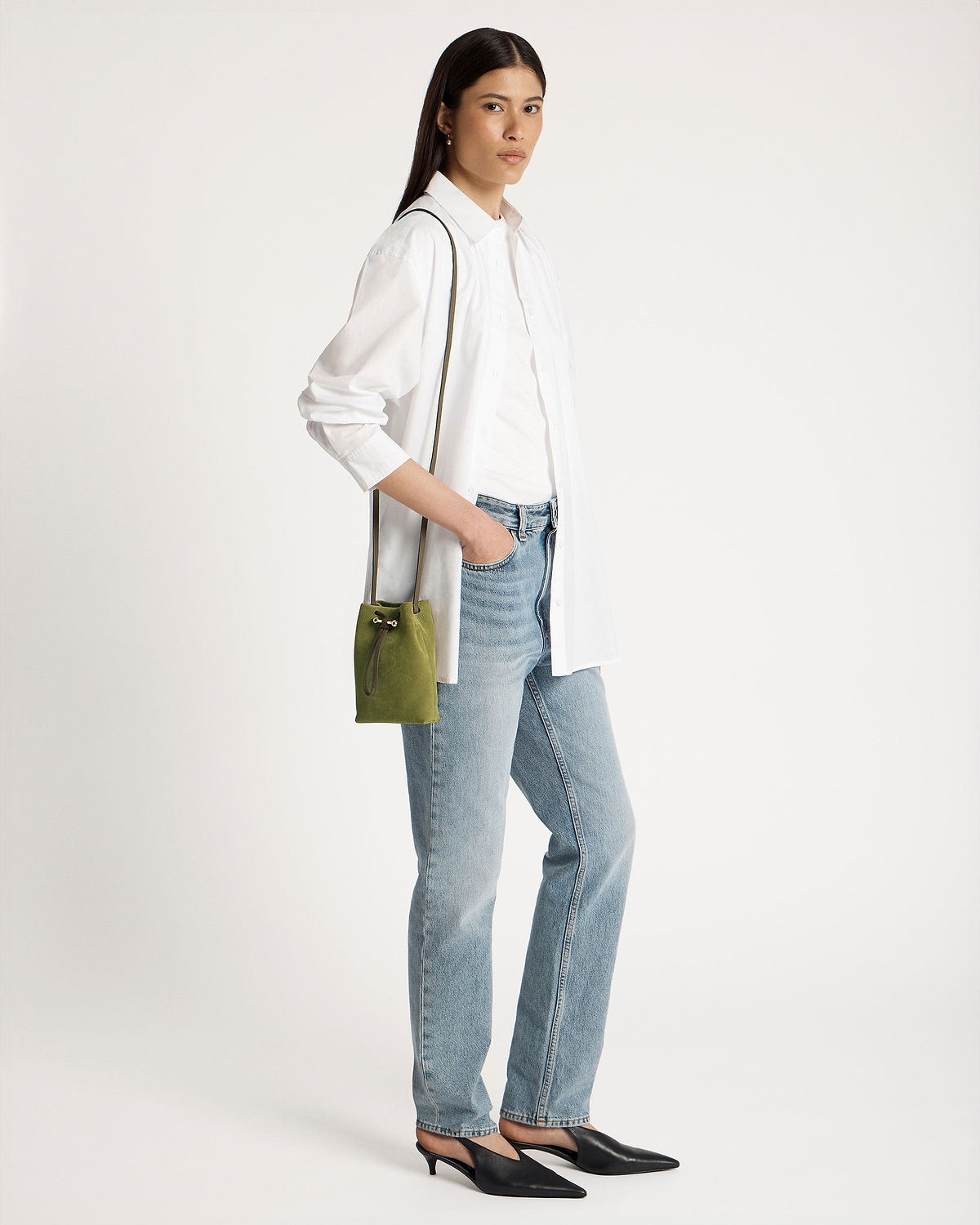 Model wearing white shirt and jeans carrying lime suede and khaki drawstring pouch.