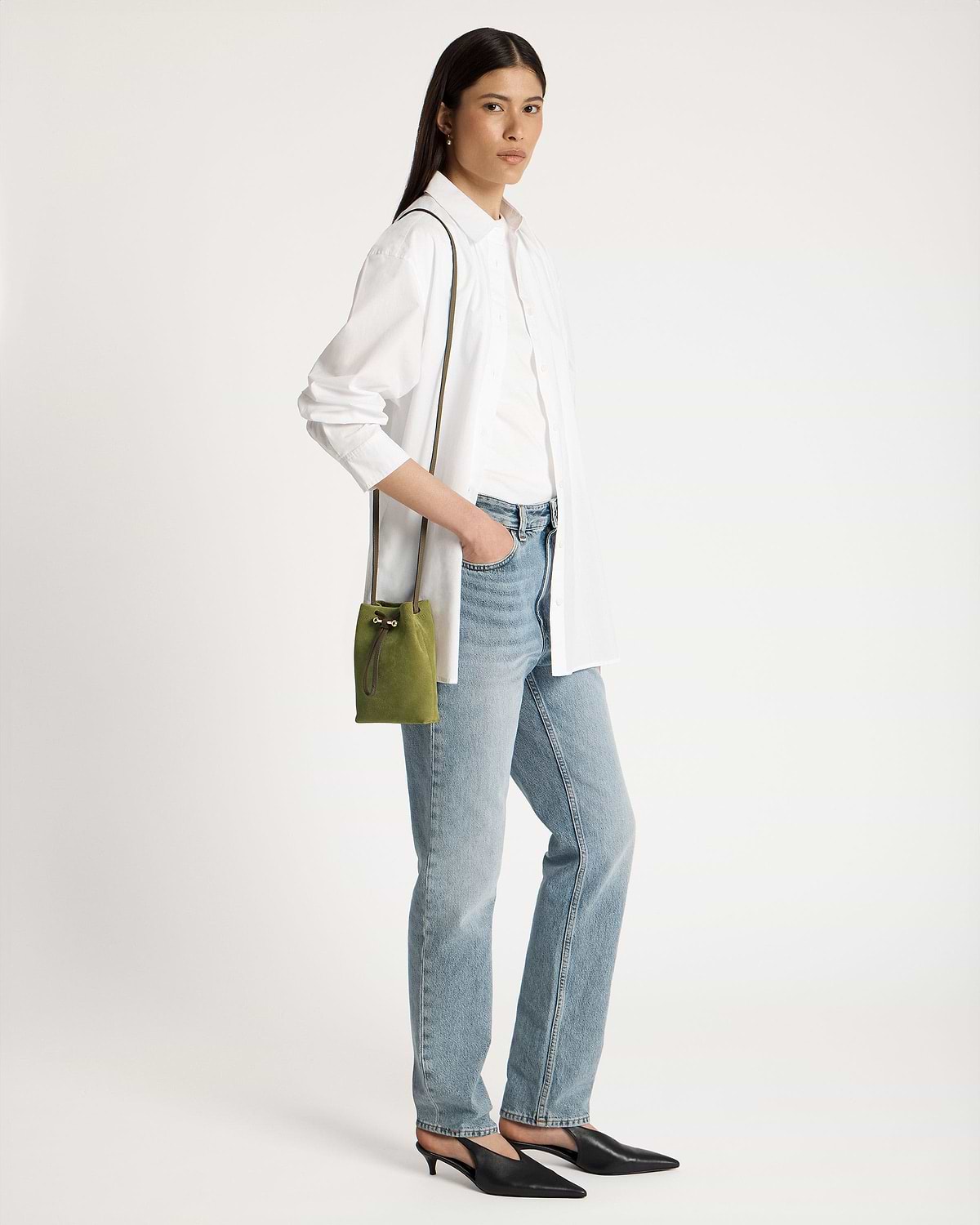 Model wearing white shirt and jeans carrying lime suede and khaki drawstring pouch.