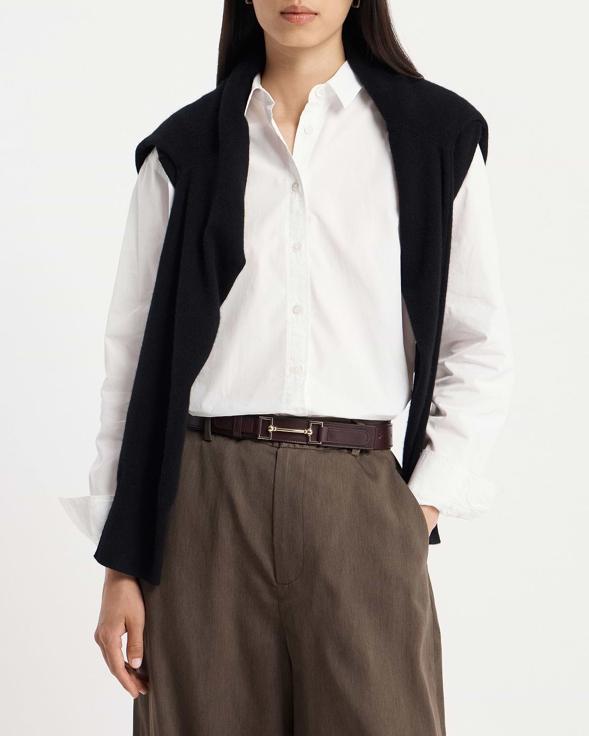 Model wearing burgundy leather belt with gold horsebit buckle, white shirt and brown trousers