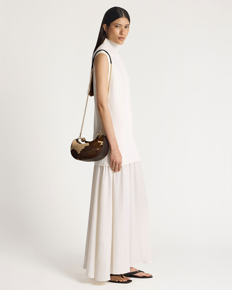 Model wearing crescent moon mini bag in sand and espresso spot print.