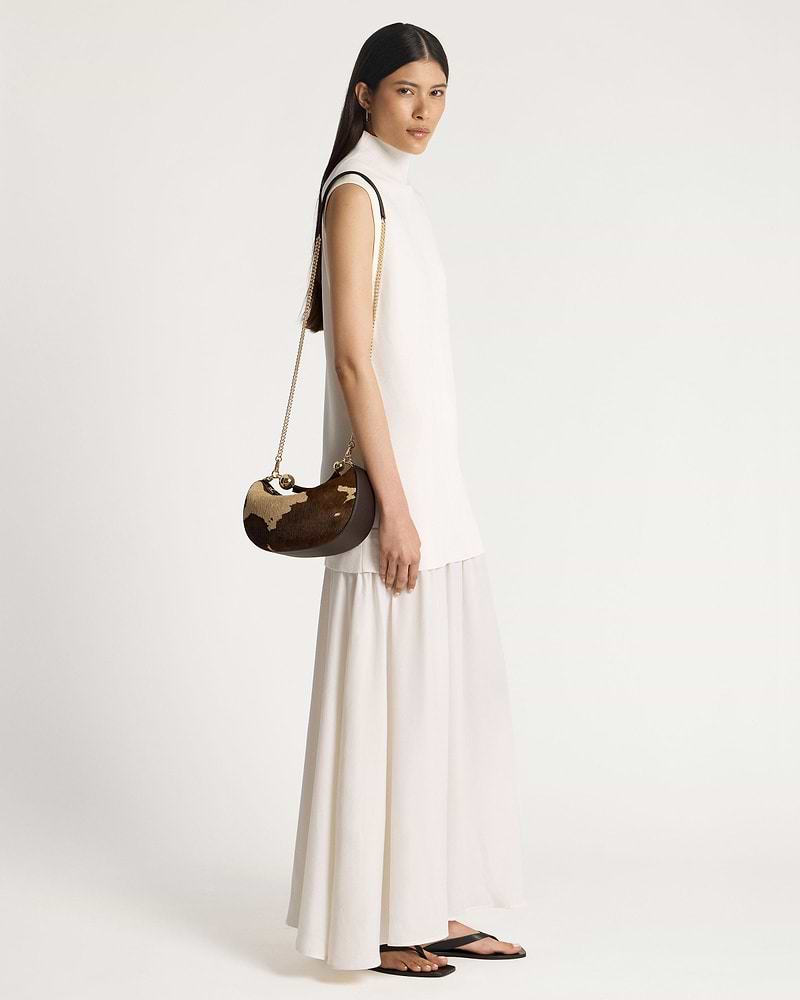 Model wearing crescent moon mini bag in sand and espresso spot print.