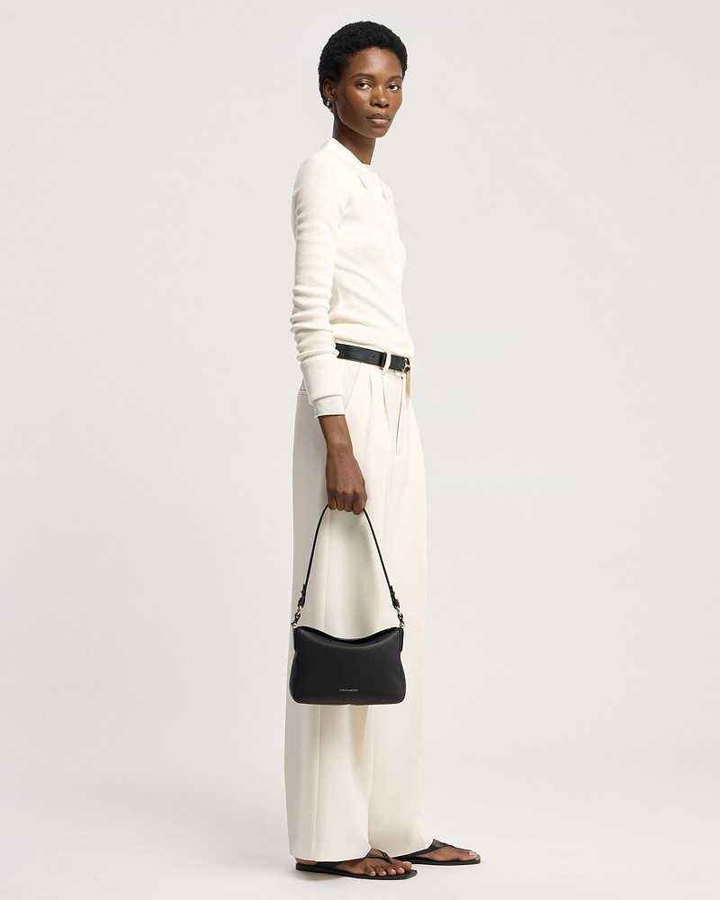 Model holding black Strathberry Sway shoulder bag at her side