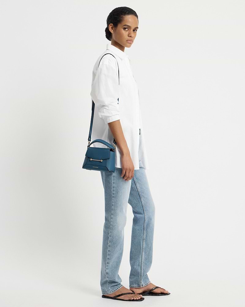 Model in white shirt and jeans carrying loch blue Mosaic Nano shoulder bag.