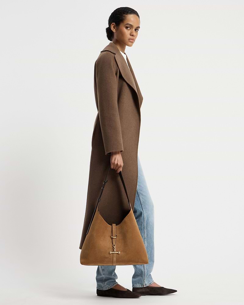 Model in brown coat holding toffee suede hobo bag with espresso strap and gold hardware.
