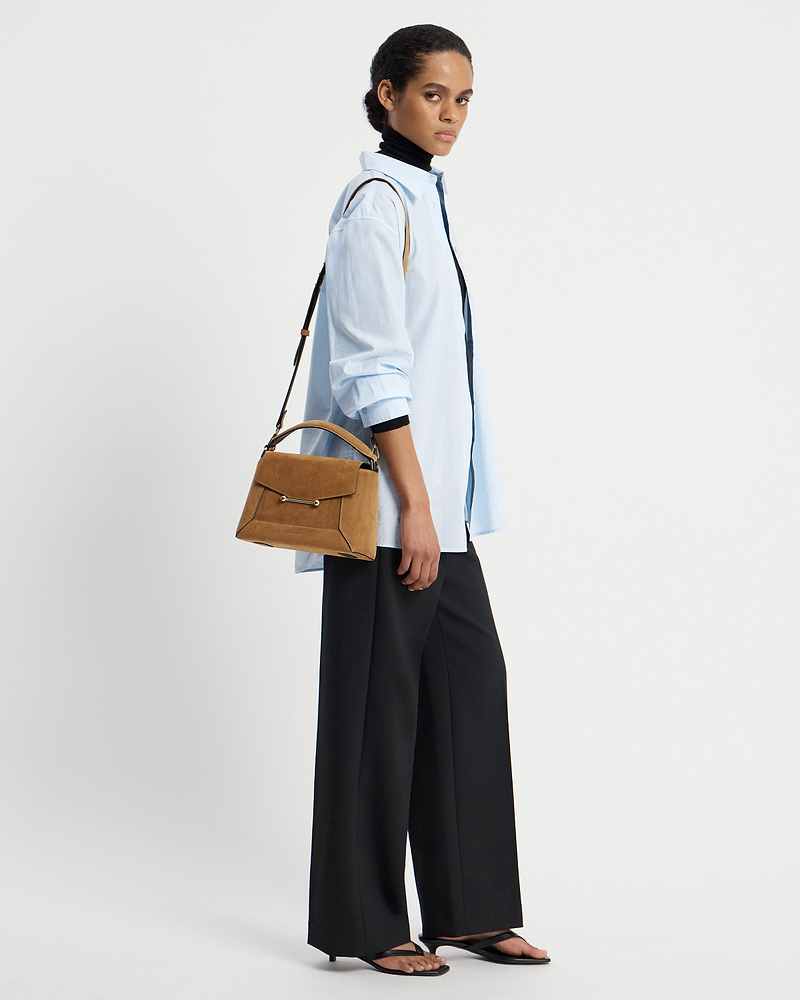 Woman wearing light blue shirt carrying toffee suede mosaic bag with espresso strap