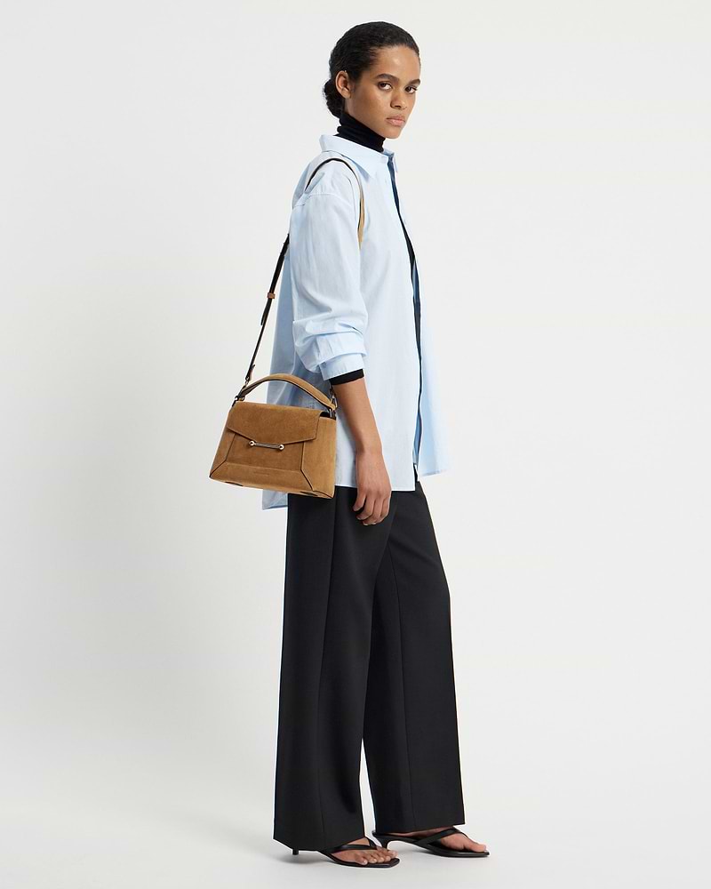 Woman wearing light blue shirt carrying toffee suede mosaic bag with espresso strap