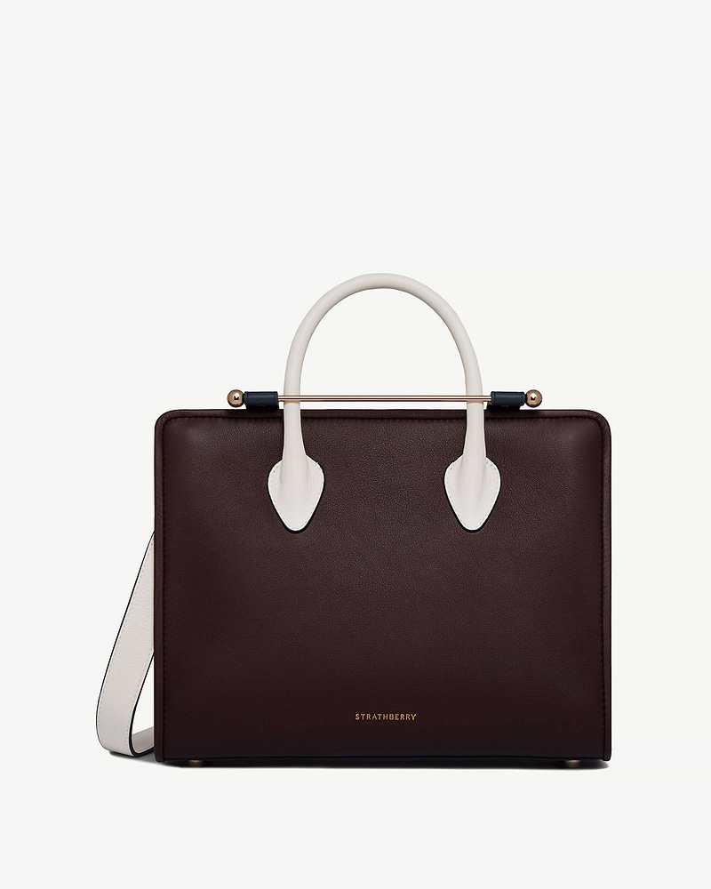 Strathberry midi tote in burgundy with vanilla handles, navy accents and gold bar.