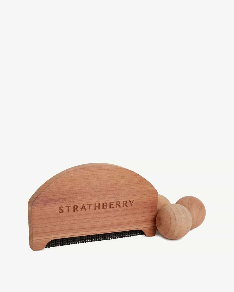 Strathberry cedar lint brush with black fabric strip and three wooden balls.