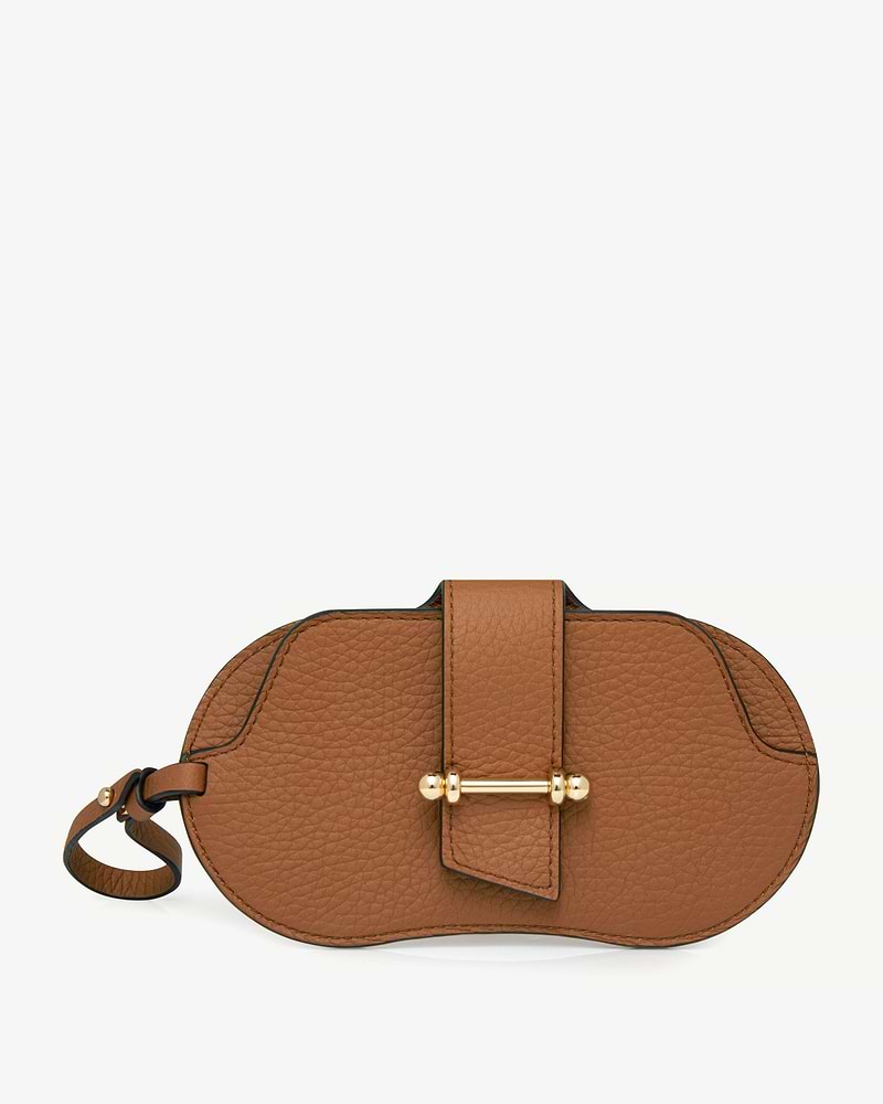 Tan pebbled leather sunglasses case with central strap, gold-bar closure and wrist loop.