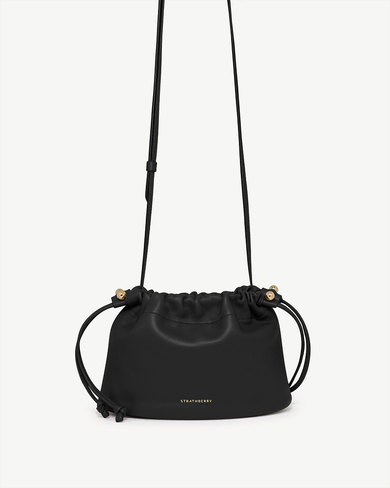 Black Charlotte drawstring bag with gold Strathberry logo and thin strap