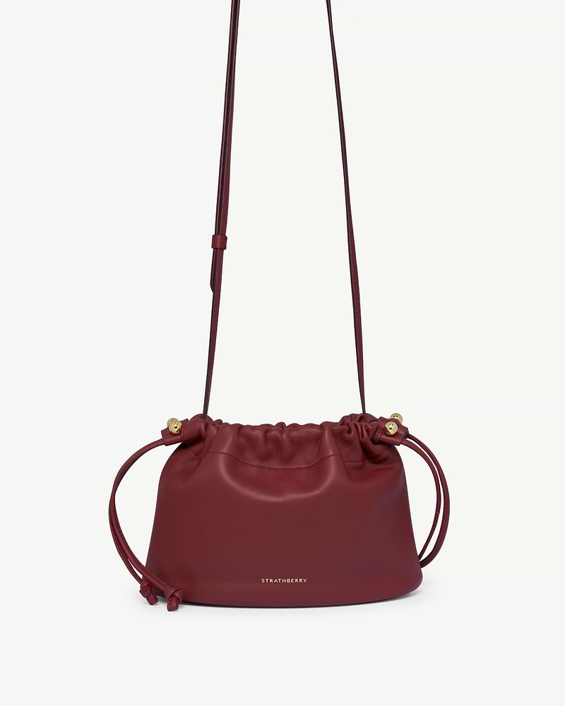 Strathberry Charlotte drawstring bag in oxblood leather with long shoulder strap.