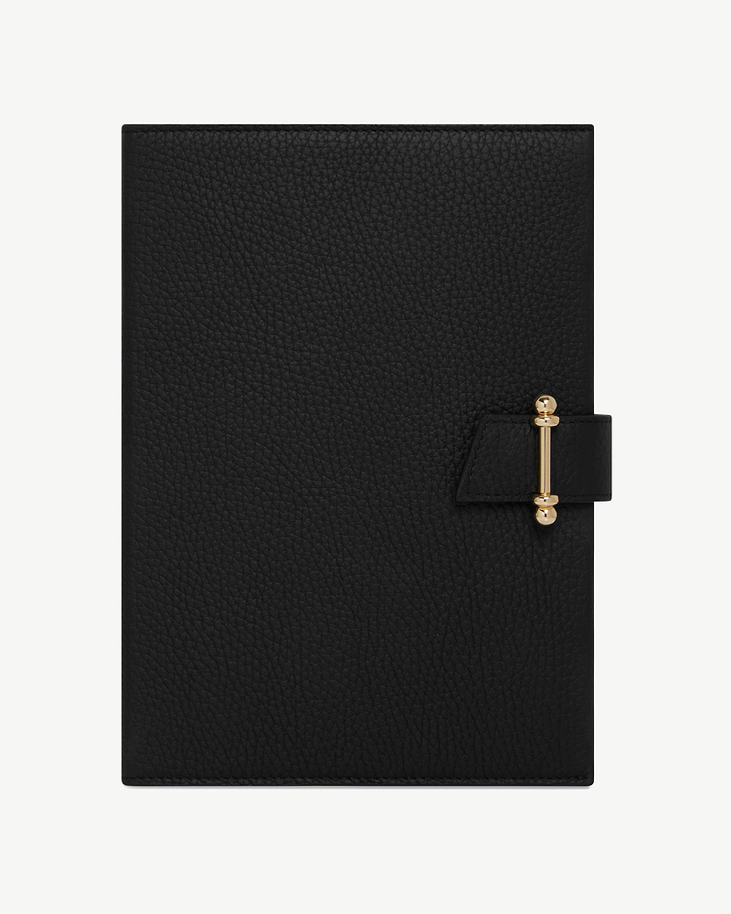 Black leather notebook with textured cover and gold clasp closure, centred on white background.