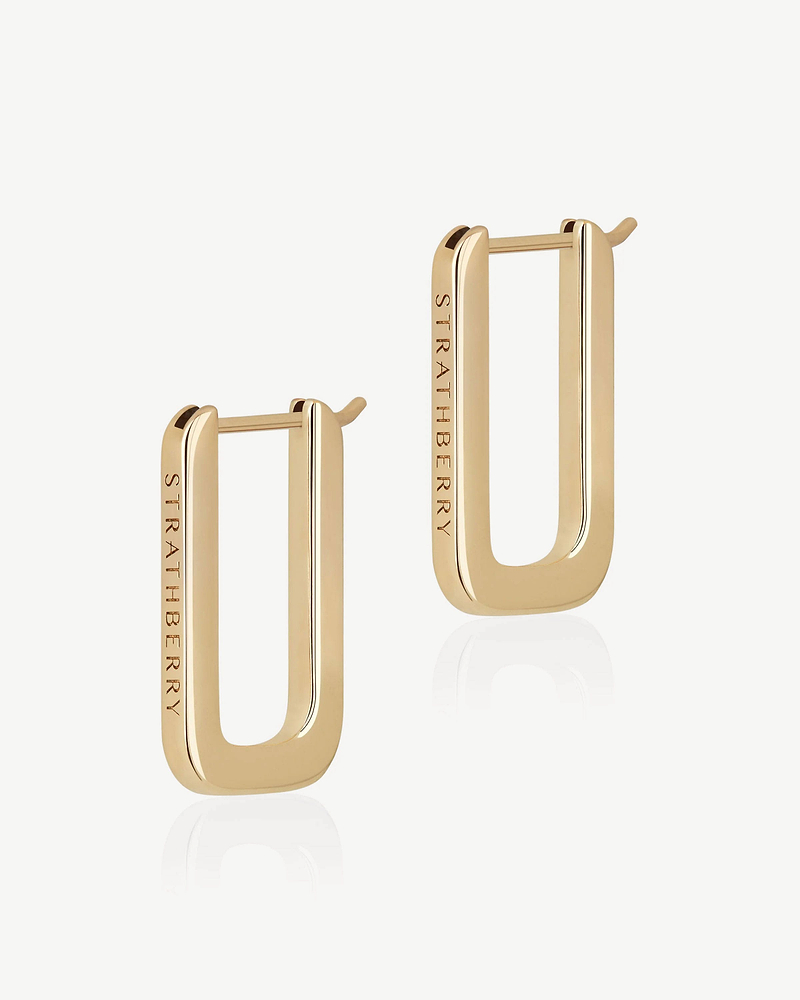 Pair of 22 carat gold rectangular hoop earrings engraved with Strathberry on white background
