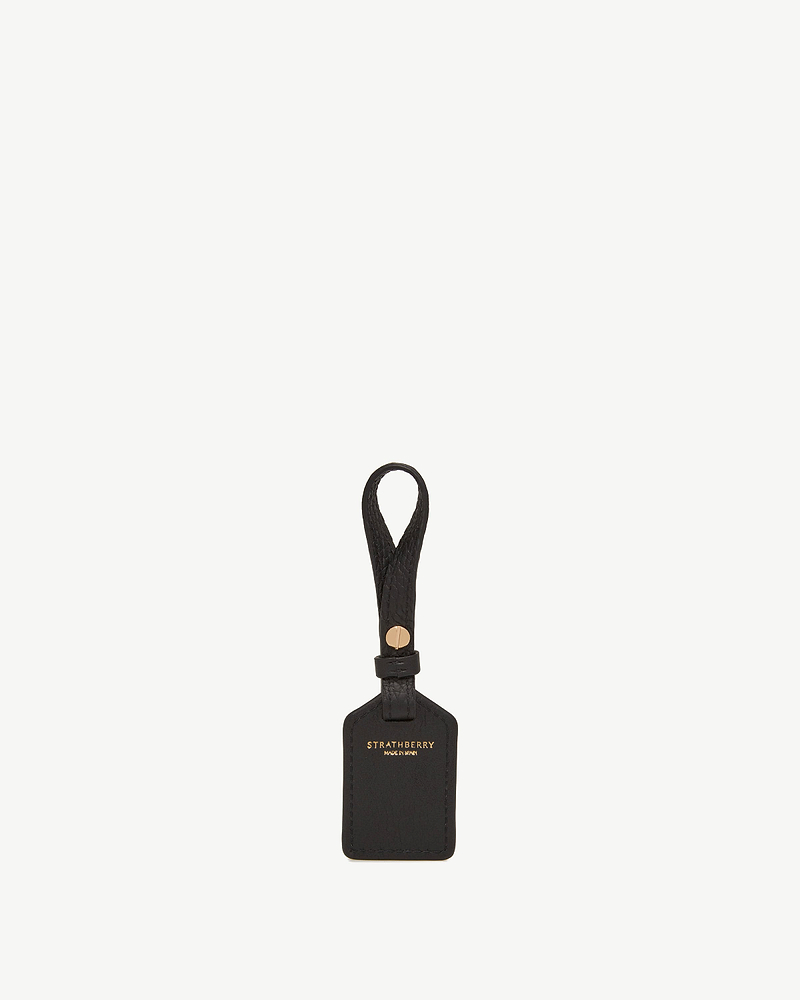 Black leather tag with looped strap and gold Strathberry logo.