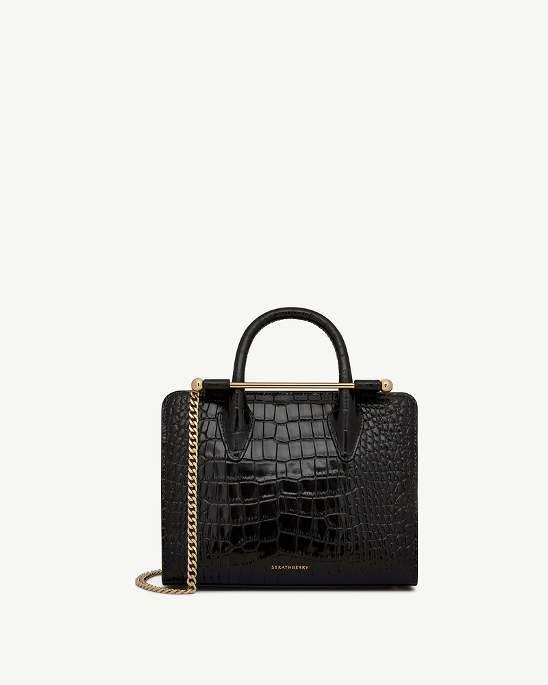 Black croc mini tote with top handles, gold bar detail and chain, Strathberry logo.