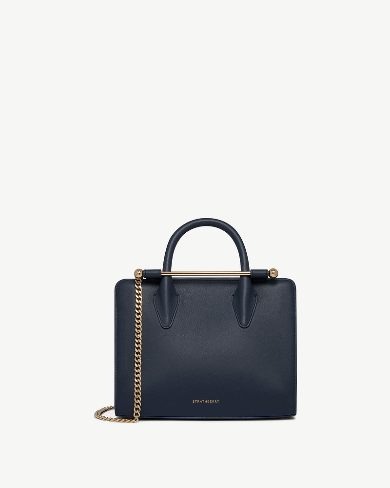 Strathberry mini tote in marine blue with gold chain strap and top handle.