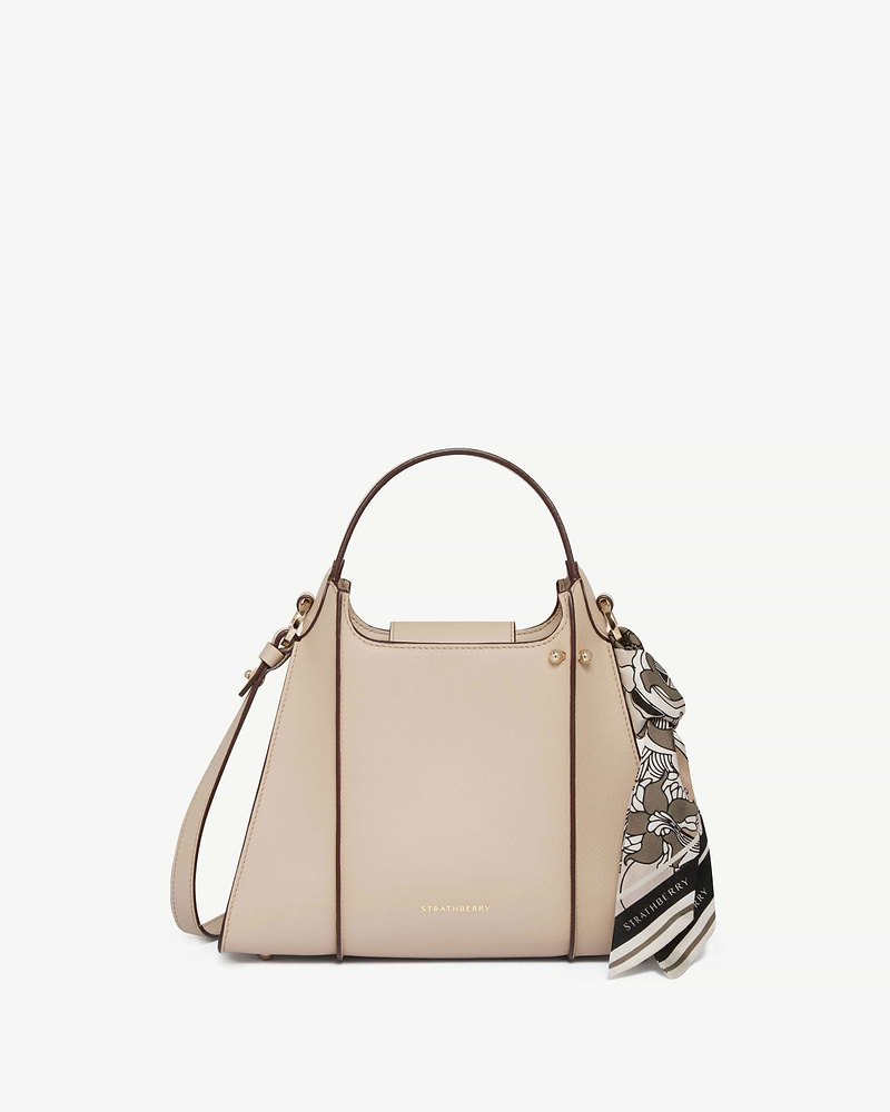 Strathberry Arkshell bag in oat with top handle, shoulder strap and patterned scarf.