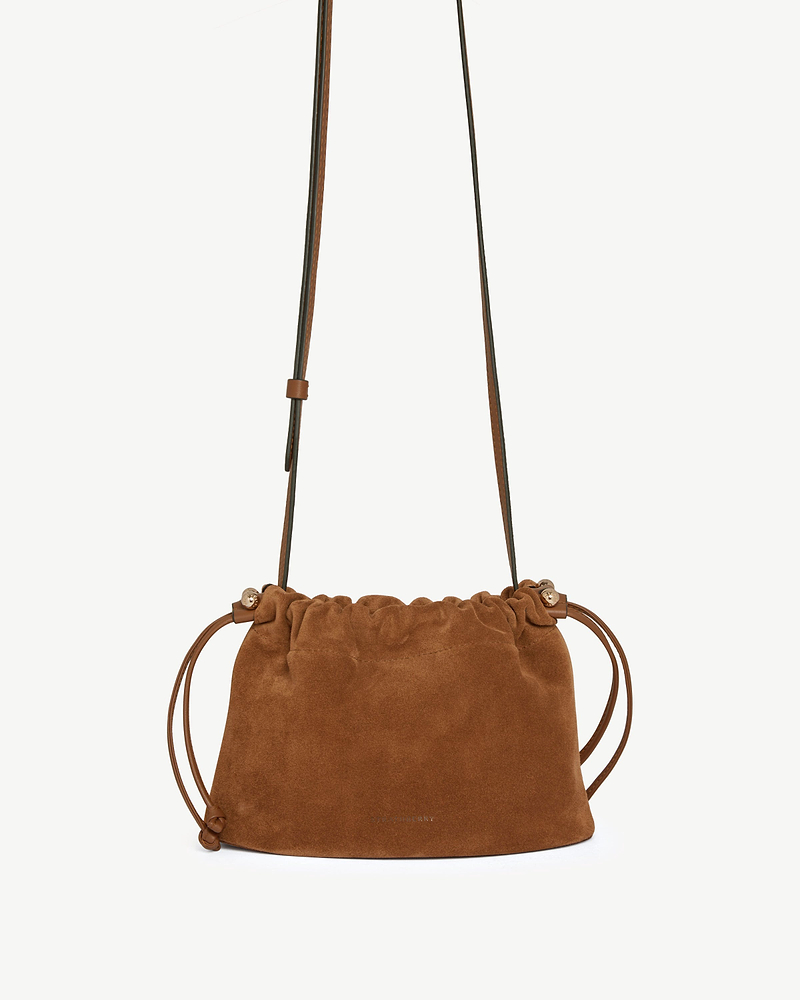 Tan suede drawstring bag with long adjustable shoulder strap and side cords.