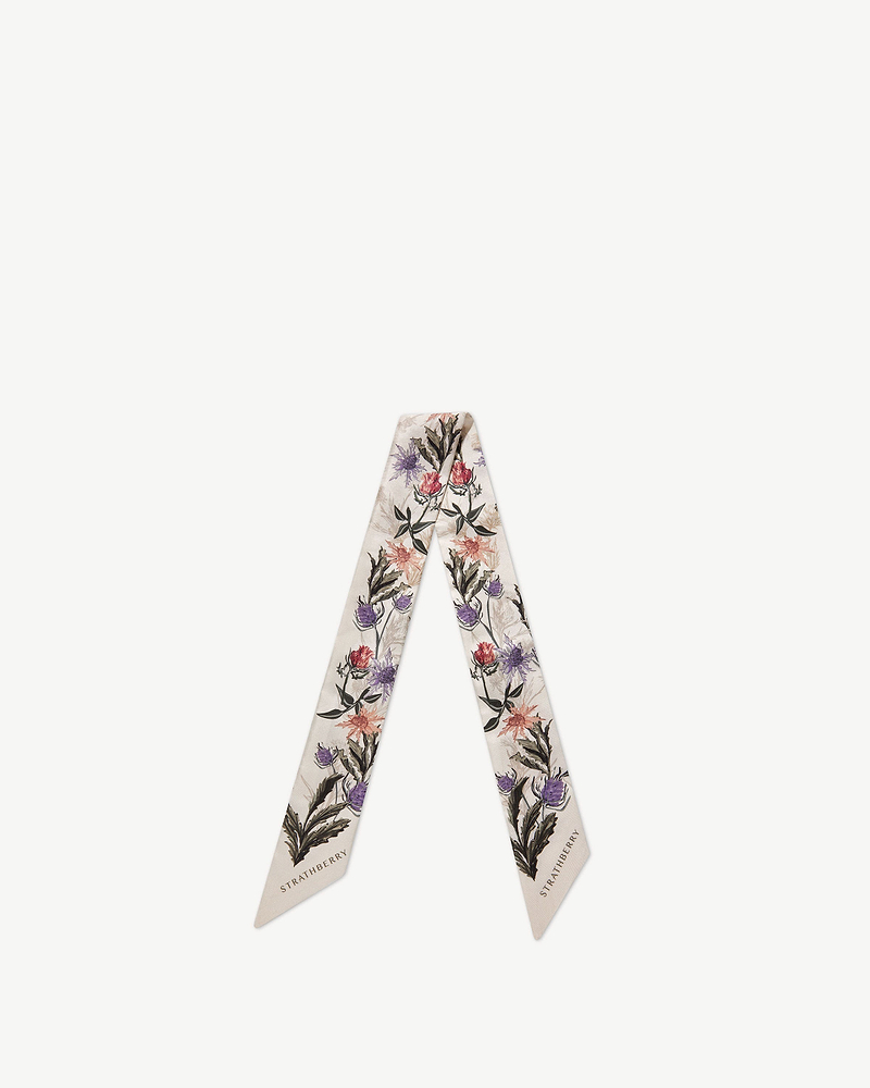 Strathberry vanilla silk skinny scarf with forest green thistle print, laid flat.