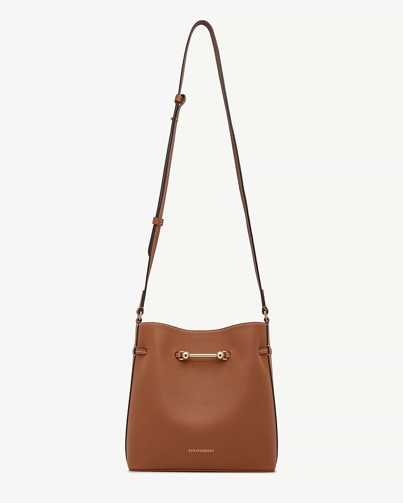 Strathberry chestnut Corda bucket bag with adjustable strap and metal bar.