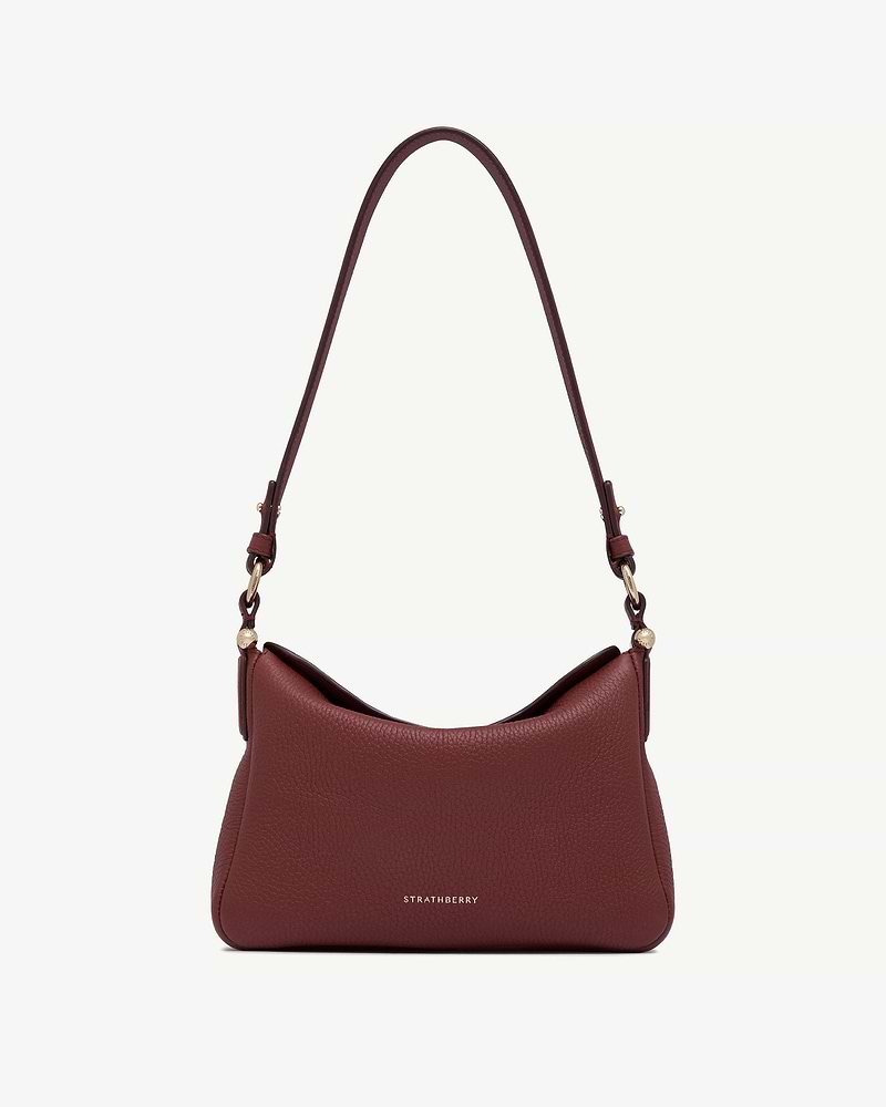 Oxblood pebbled leather shoulder bag with curved strap and gold Strathberry logo.