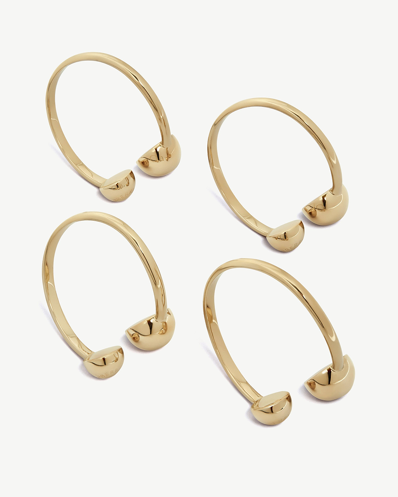 Four light gold metal napkin holders displayed on a plain white background.