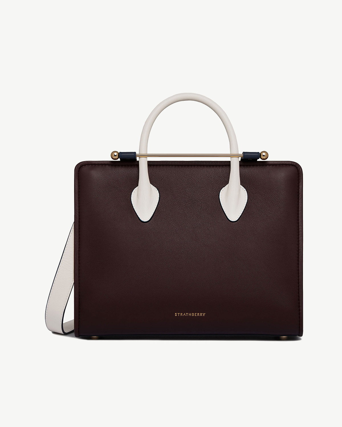 Front of burgundy midi tote with vanilla-coloured handles, navy bar and Strathberry logo.
