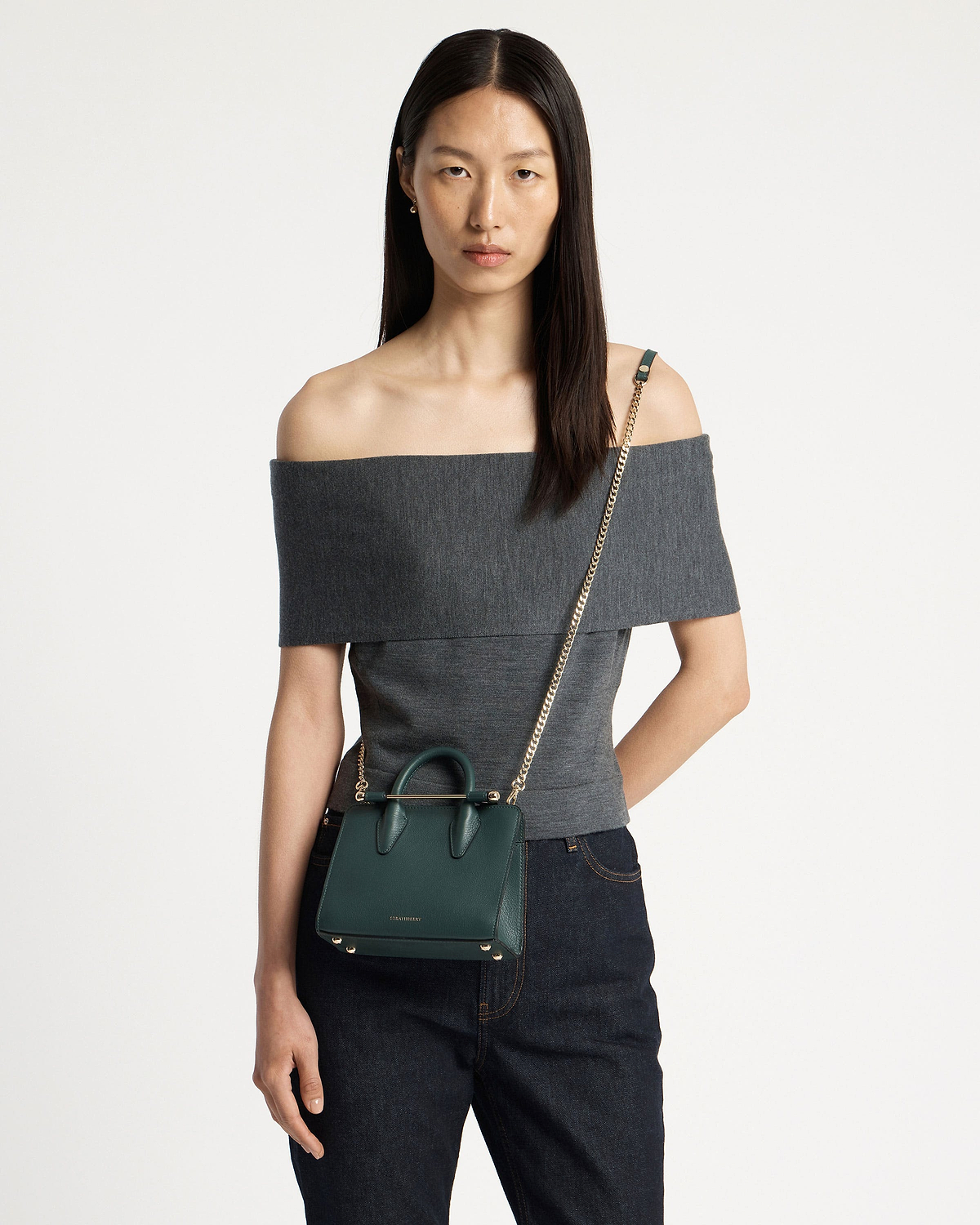 Model wearing bottle green Strathberry nano tote with gold chain crossbody strap.