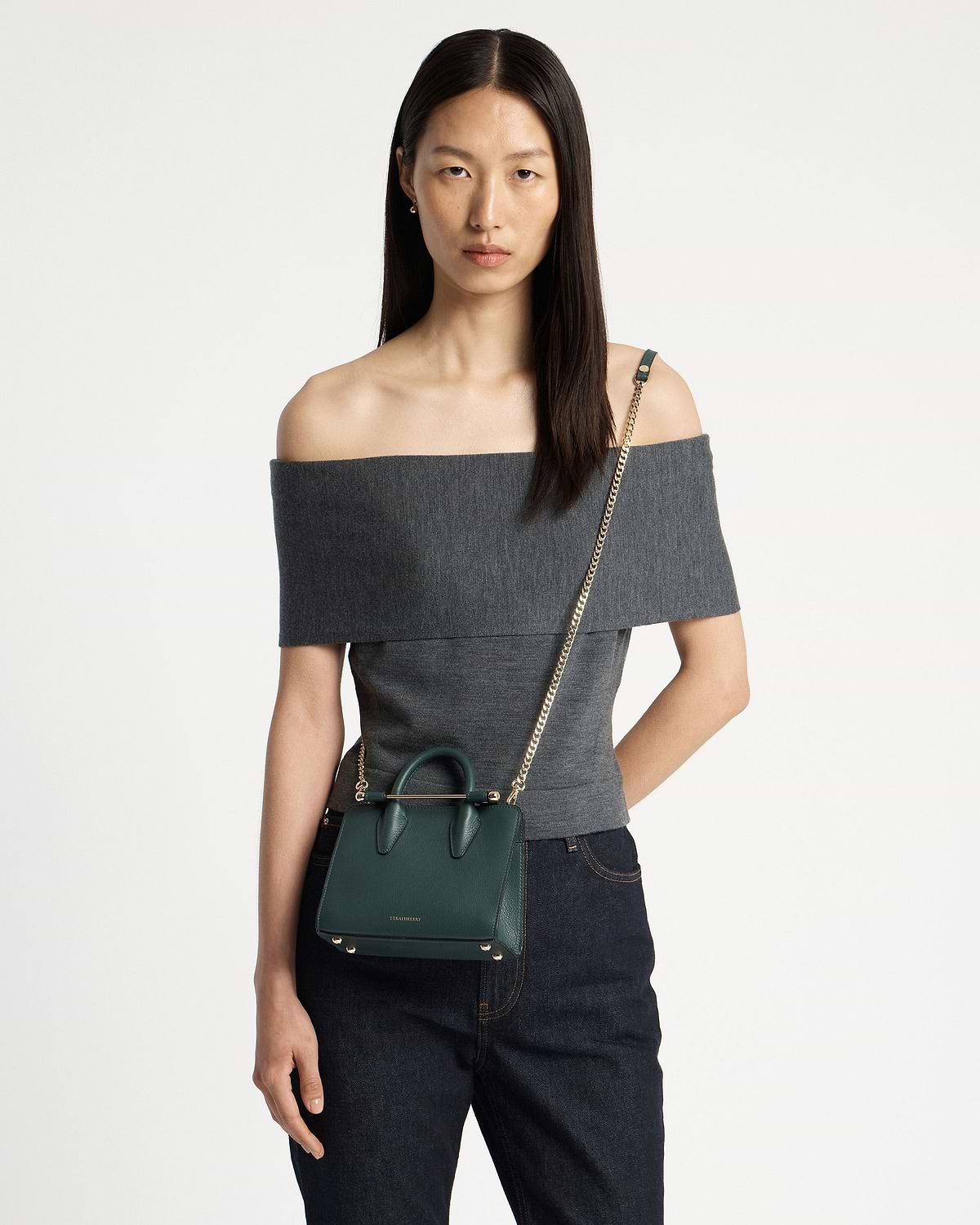 Model wearing bottle green Strathberry nano tote with gold chain crossbody strap.