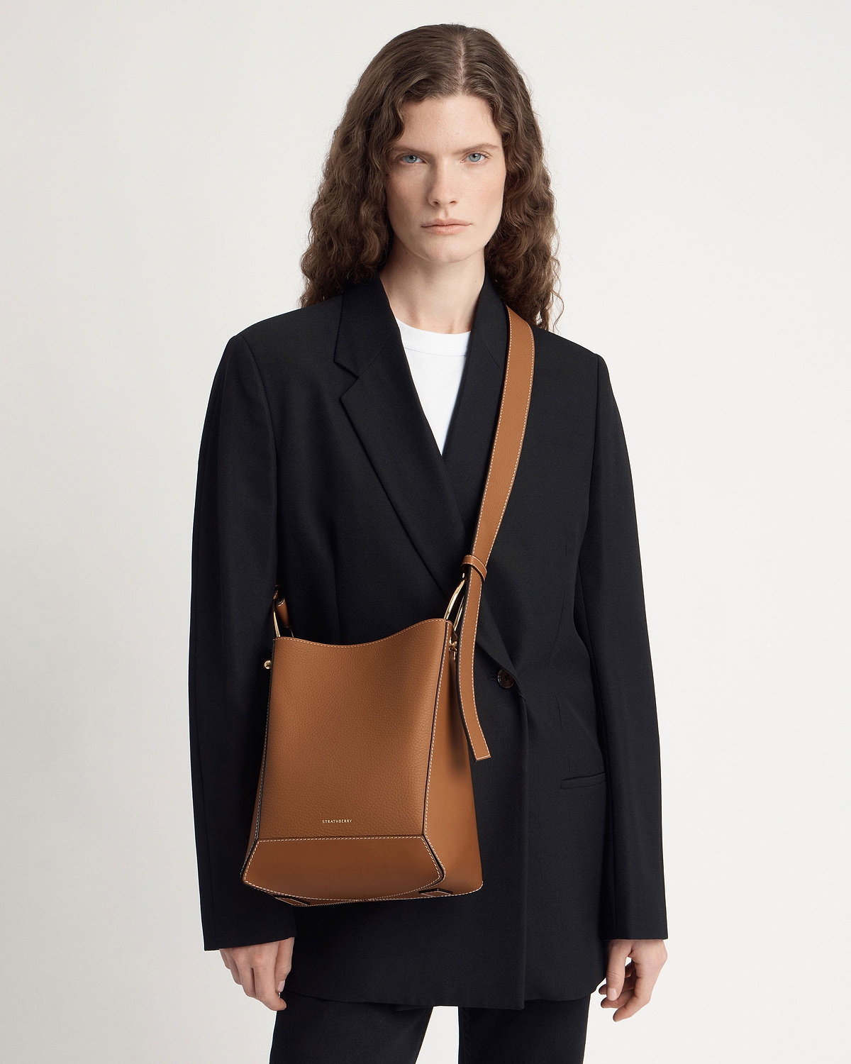 Model wearing tan Strathberry Lana midi bucket bag with vanilla contrast stitching