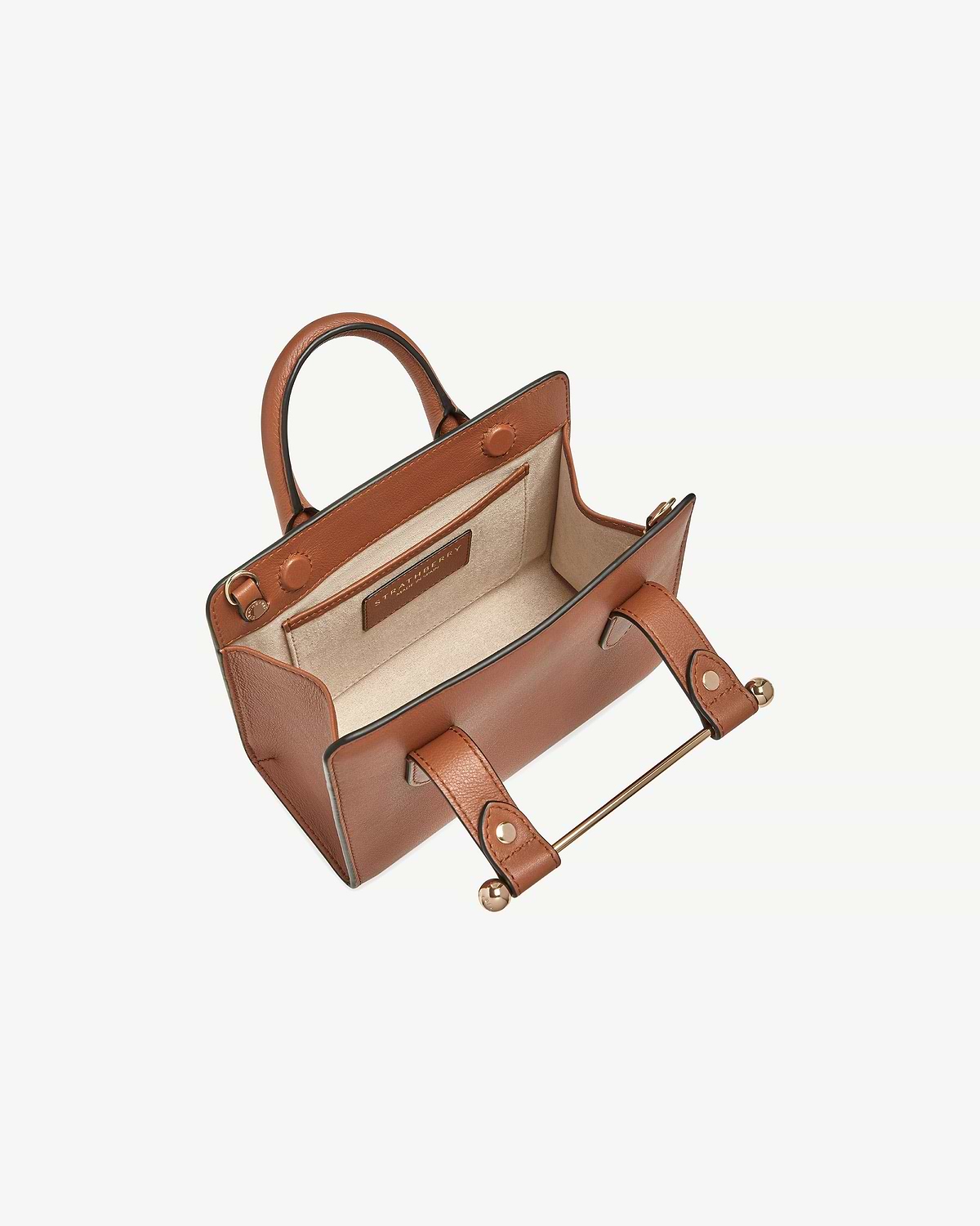 Chestnut Strathberry nano tote, open with beige interior and gold bar handle.