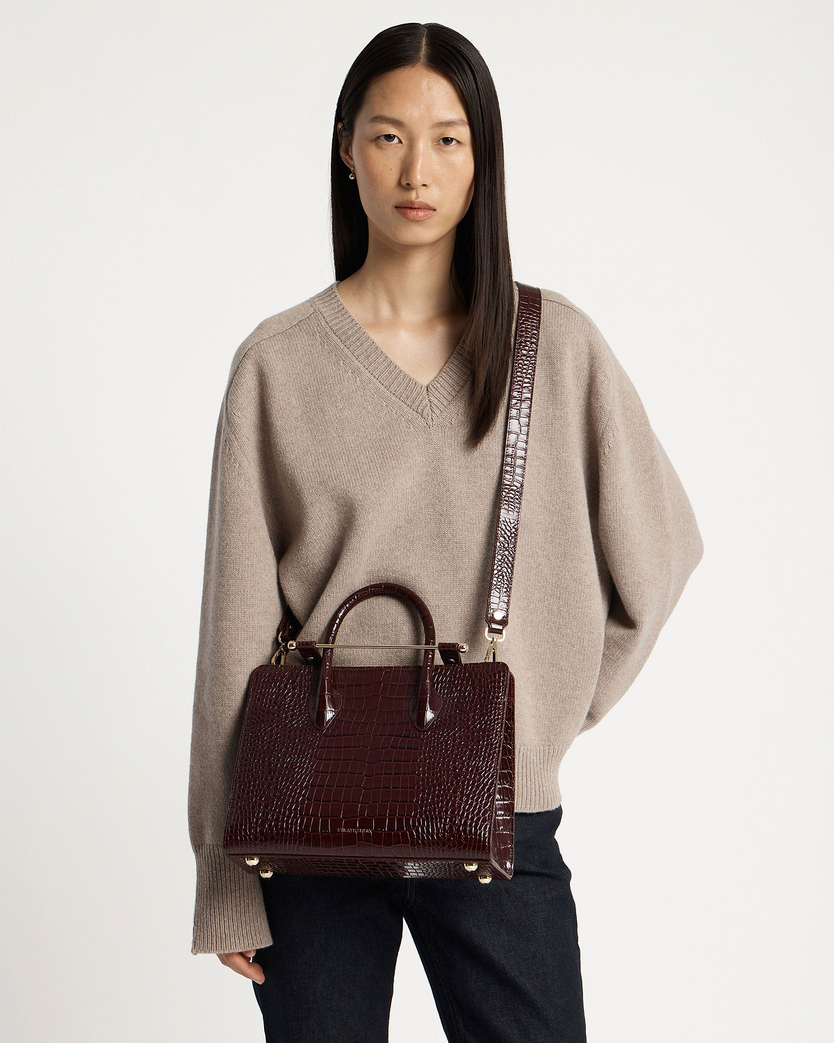Model wearing a croc-embossed midi tote with long shoulder strap.