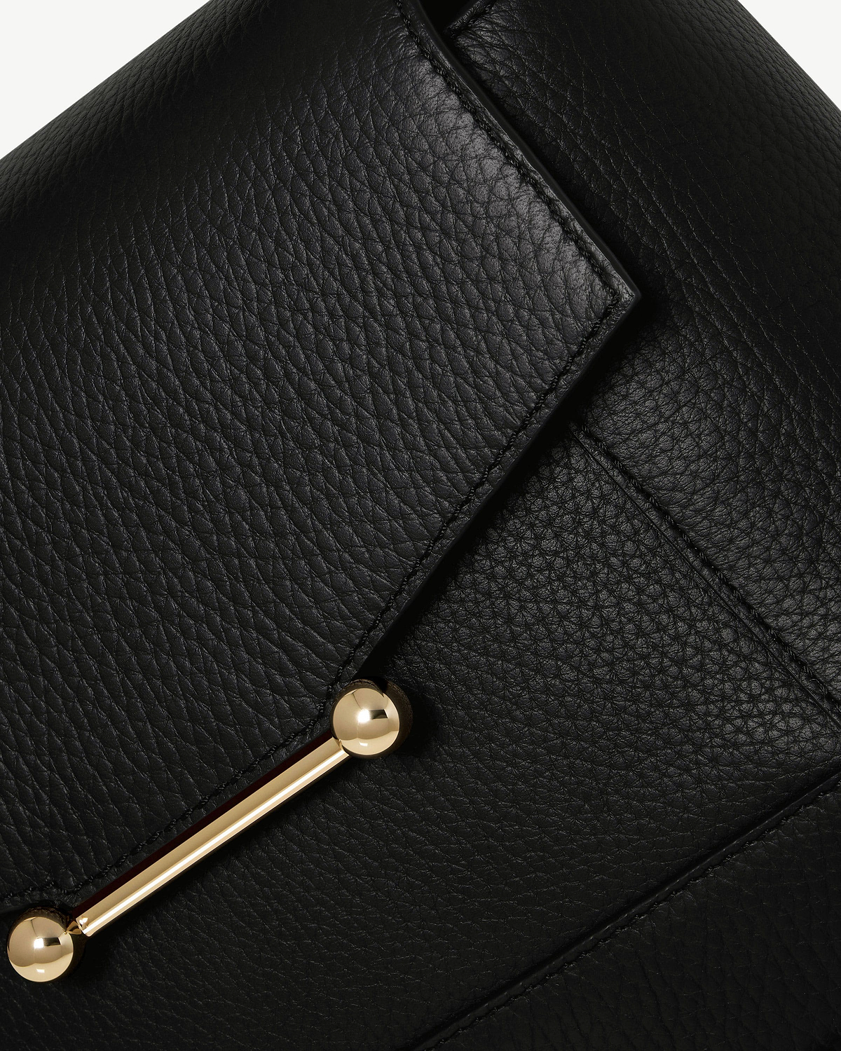 Close up of black pebbled leather mosaic bag flap with gold bar hardware.