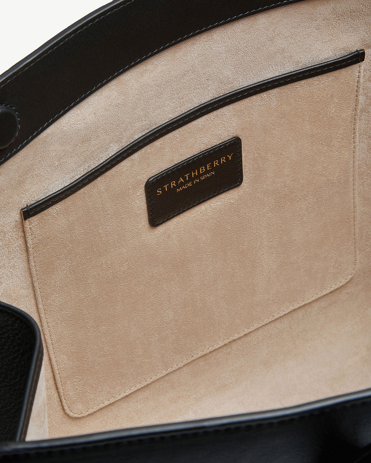 Tote interior showing beige suede pocket and black Strathberry label reading 'Made in Spain'.