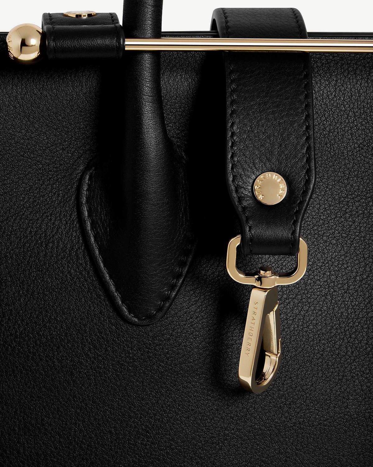 Black leather midi tote strap and handle with gold Strathberry engraved clasp hardware.