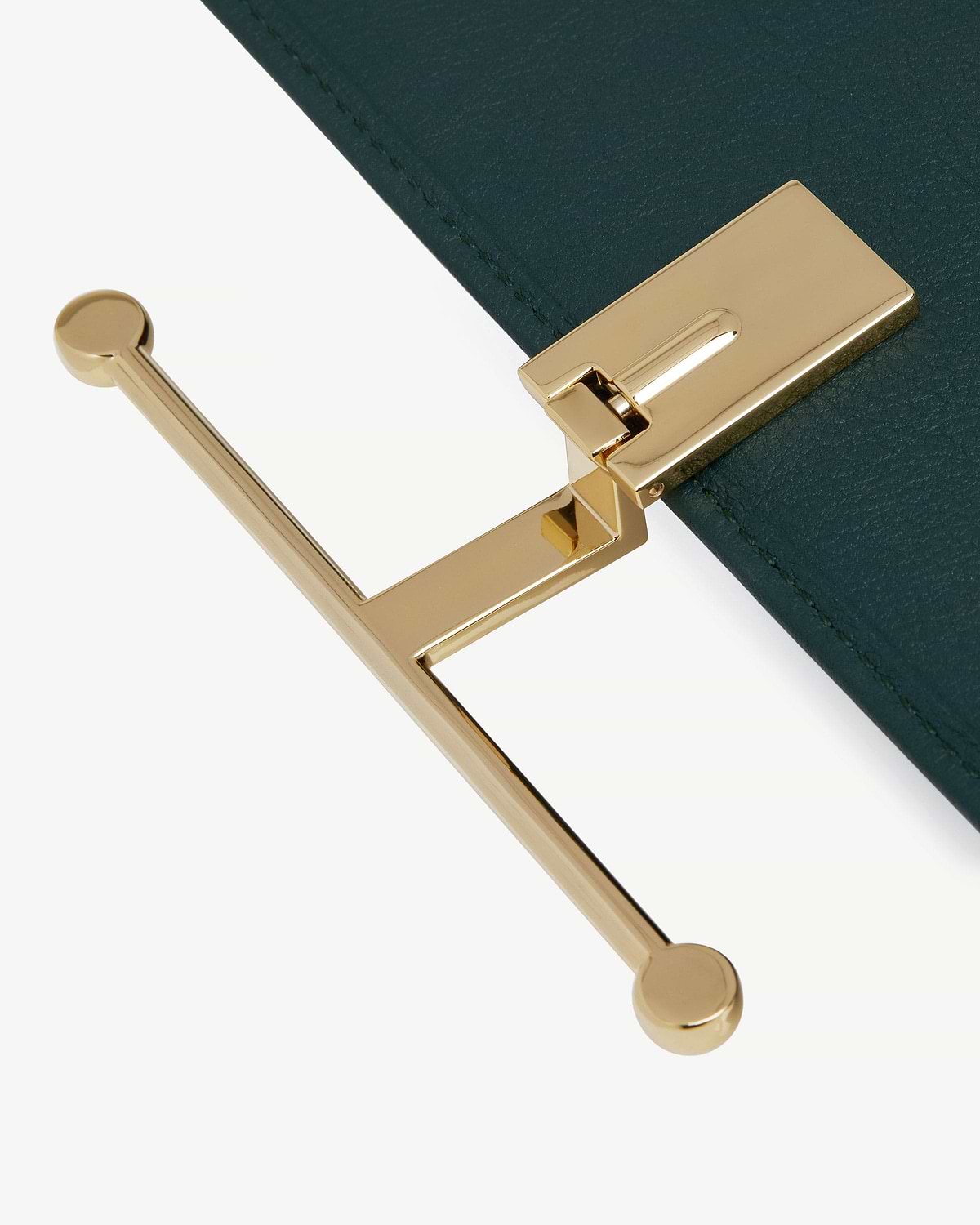 Close-up of bottle green leather wallet showing gold T-bar clasp hardware.