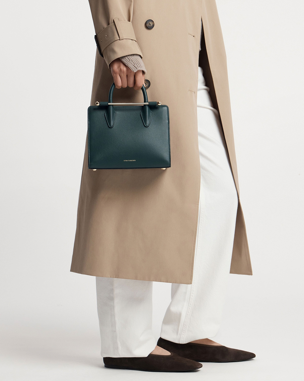 Strathberry bottle green mini tote held by model in beige coat.